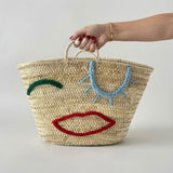 Woven Straw Market Tote Bag with Embroidered Winking Face Design